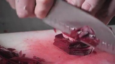 El bıçak kesim taze sebze ile closeup. Genç Şef kesme pancar beyaz kesme pano portre üzerinde. Bir restoran mutfağında yemek