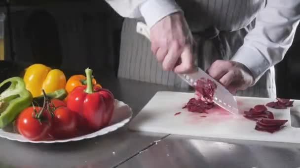 Крупный план руки с ножом, обрезающим свежий овощ. Молодой шеф-повар режет свеклу на белой доске крупным планом. Кулинария на кухне ресторана — стоковое видео
