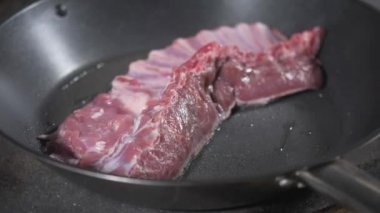 Kızarmış pirzola kuzu. bir Bahar Dalı, biberiye ve sarımsak ekleyin. Ateşle tavada pişirme. Profesyonel şef yemek Restoran bir mutfak. Adam yemek hob üzerinde yanan tavada kızartma.
