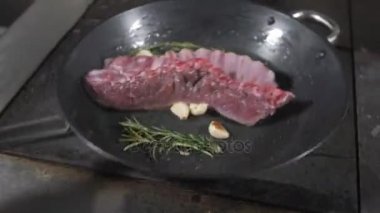 Kızarmış pirzola kuzu. bir Bahar Dalı, biberiye ve sarımsak ekleyin. Ateşle tavada pişirme. Profesyonel şef yemek Restoran bir mutfak. Adam yemek hob üzerinde yanan tavada kızartma.