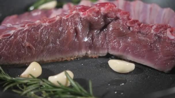 Costolette di agnello fritte. aggiungere un rametto di rosmarino e aglio. Cucinare con il fuoco in padella. Chef professionista in una cucina di cucina ristorante. L'uomo frigge il cibo in padella fiammeggiante sul piano cottura . — Video Stock