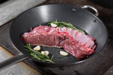 Kızarmış pirzola kuzu. bir Bahar Dalı, biberiye ve sarımsak ekleyin. Ateşle tavada pişirme. Profesyonel şef yemek Restoran bir mutfak. Adam yemek hob üzerinde yanan tavada kızartma.