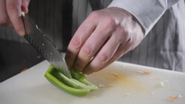 El bıçak kesim taze sebze ile closeup. Genç Şef kesme kırmızı biber beyaz kesme pano portre üzerinde. Bir restoran mutfağında yemek