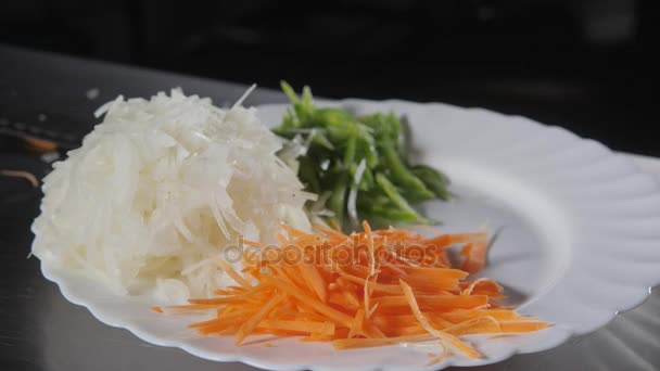 与刀切新鲜蔬菜的手特写。年轻厨师切洋葱的白色切割板特写。在餐馆厨房做饭 — 图库视频影像