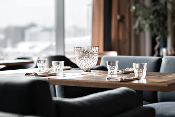 Mesa en restaurante servida para el almuerzo. Vasos, tenedor de flores, cuchillo servido para la cena en el restaurante con interior acogedor — Foto de Stock