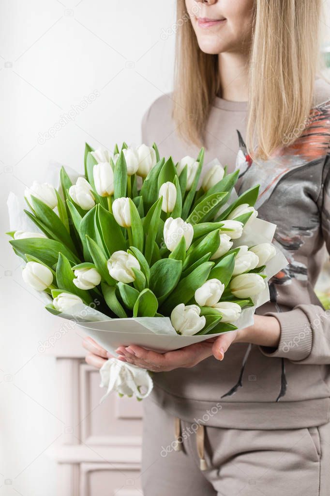 beautiful luxury bouquet of white tulips flowers in woman hand. the work of the florist at a flower shop. cute lovely girl