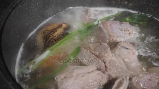 Caldo de carne tradicional com vegetais, ossos e ingredientes em panela, receita de cozinha. Sopa em uma panela de cozinha com concha no fundo de pedra escura. Vista superior — Vídeo de Stock