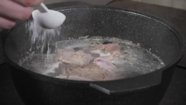 Chef cucinare il sale. brodo di manzo tradizionale con verdure, ossa e ingredienti in pentola, ricetta di cottura. Zuppa in pentola con mestolo su fondo pietra scura. Vista dall'alto — Video Stock