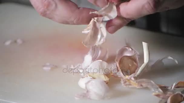 Primo piano di mano con coltello che taglia aglio fresco. Giovane chef taglio cavolo su un tagliere bianco primo piano. Cucinare in una cucina ristorante — Video Stock