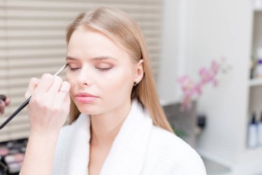 Boya gözler. Makyaj sanatçısı güzel makyaj sarışınlar modeli oluşturma. Güzellik ve Spa merkezi kavramı