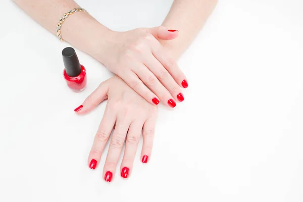 Mani femminili con manicure e lacca rossa su un tavolo bianco nel salone di bellezza. primo piano di mano di una giovane donna . — Foto Stock