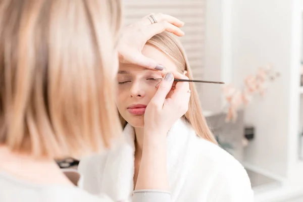 Barva oči. Maskérka vytváří krásný make-up pro blondýnky modelu. Krása a wellness centrum koncepce — Stock fotografie