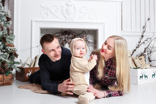 Šťastná rodina o Vánocích. Rodiče a dítě ležící na podlaze a usmívá se. — Stock fotografie