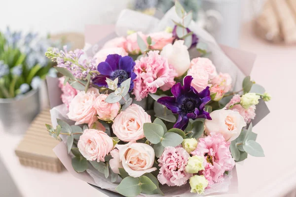 Schöner luxuriöser Strauß gemischter Blumen auf rosa Tisch. die Arbeit der Floristin in einem Blumenladen. — Stockfoto