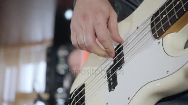 Close up on the fingers of young man playing bass guitar on the stage — Stock Video