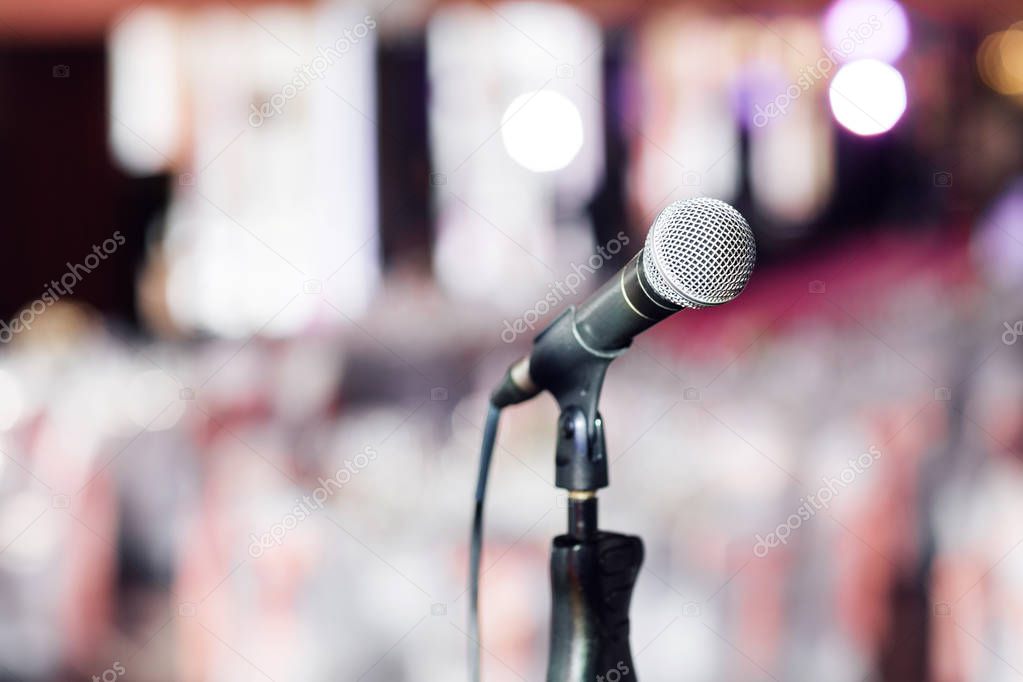 Microphone close-up. Focus on mic. Abstract blurred conference hall or wedding banquet on background. Event concept