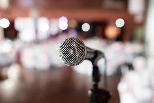 Primer plano del micrófono. Céntrate en el micrófono. Sala de conferencias borrosa abstracta o banquete de boda en el fondo. Concepto de evento — Foto de Stock