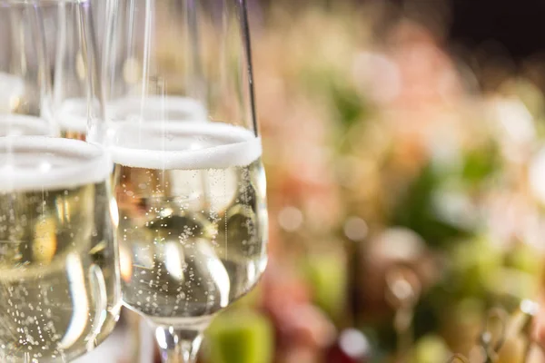 Furshet. Mesa llena de copas de vino blanco espumoso con canapés y antipasti en el fondo. burbujas de champán —  Fotos de Stock
