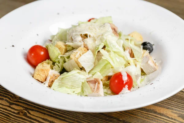 Tavuklu Sezar salata marul ile beyaz kapta tahta masada bırakır. — Stok fotoğraf