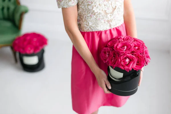 Mädchen steht und hält schwarze Schachteln mit rosa Rosen in der Hand. Mode-Stil Studio Porträt. Luxus im Innenraum — Stockfoto