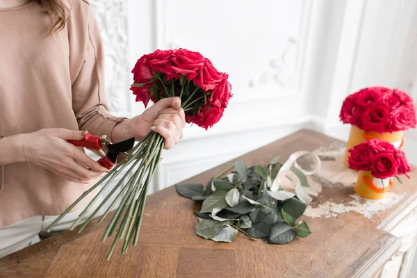 Joven florista arreglando plantas en floristería. Concepto de personas, negocios, venta y floristería. Ramo de rosas rojas — Foto de Stock