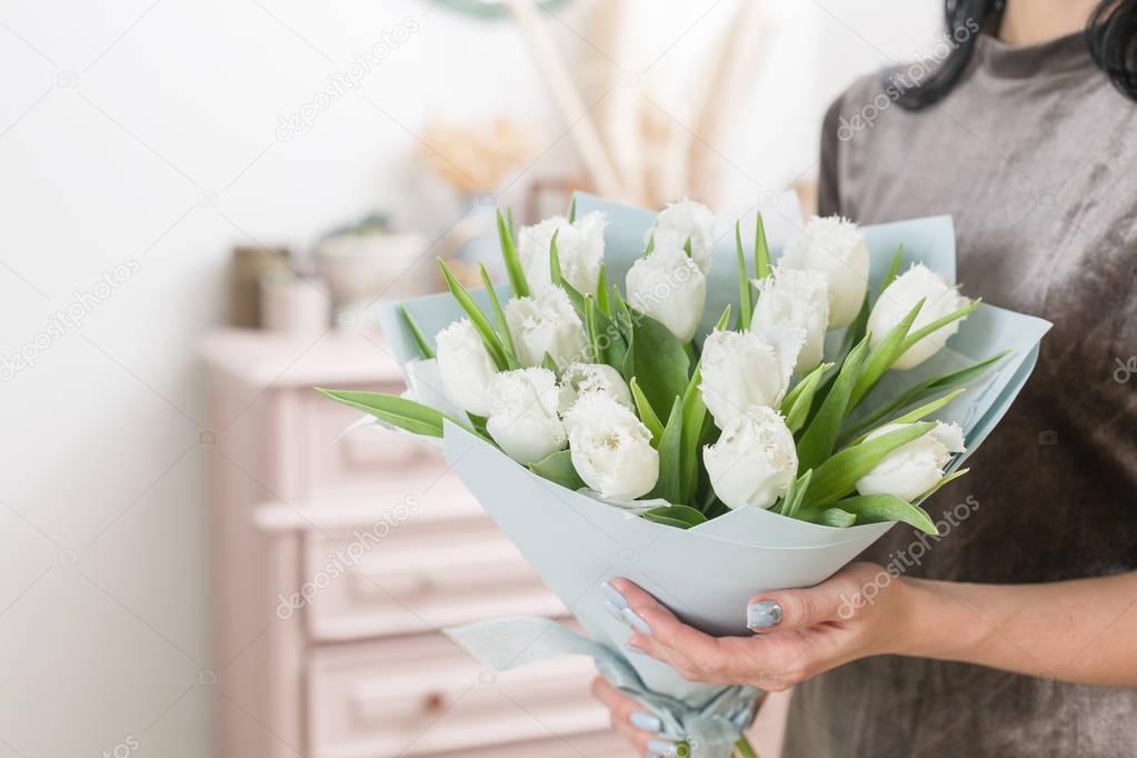 beautiful luxury bouquet of white tulips flowers in woman hand. the work of the florist at a flower shop.
