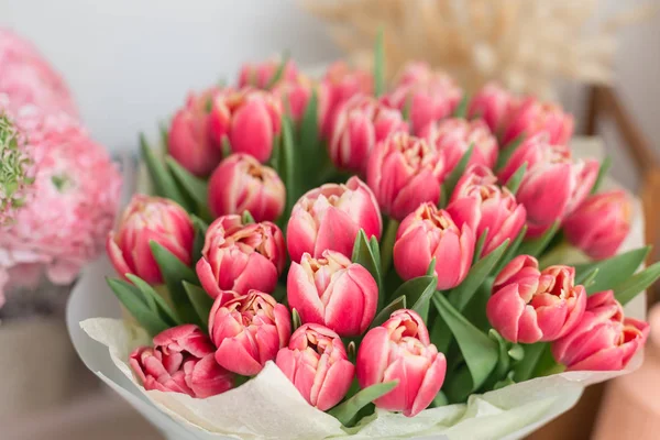 Schöner luxuriöser Strauß rosa Tulpenblüten auf dem Tisch. die Arbeit der Floristin in einem Blumenladen. — Stockfoto