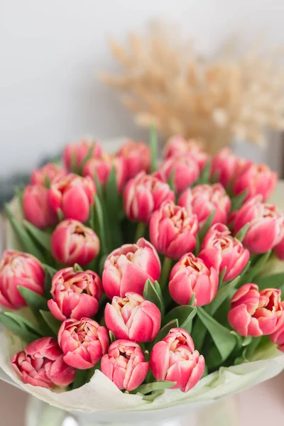 Schöner luxuriöser Strauß rosa Tulpenblüten auf dem Tisch. die Arbeit der Floristin in einem Blumenladen. — Stockfoto