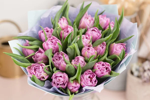 Nahaufnahme. schöner luxuriöser Strauß lila Tulpenblüten auf dem Tisch. die Arbeit der Floristin in einem Blumenladen. — Stockfoto