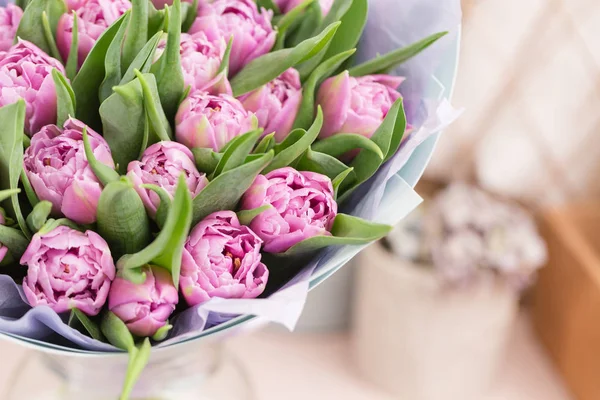 Nahaufnahme. schöner luxuriöser Strauß lila Tulpenblüten auf dem Tisch. die Arbeit der Floristin in einem Blumenladen. — Stockfoto