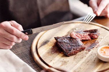 adam bir bıçakla restoranda mermer sığır eti, ızgara biftek keser. Ahşap bir gemide hizmet.