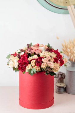 Güzel lüks kırmızı kutusunda karışık çiçekli buket. Çiçekçi Çiçek dükkanında çalışır. Duvar kağıdı
