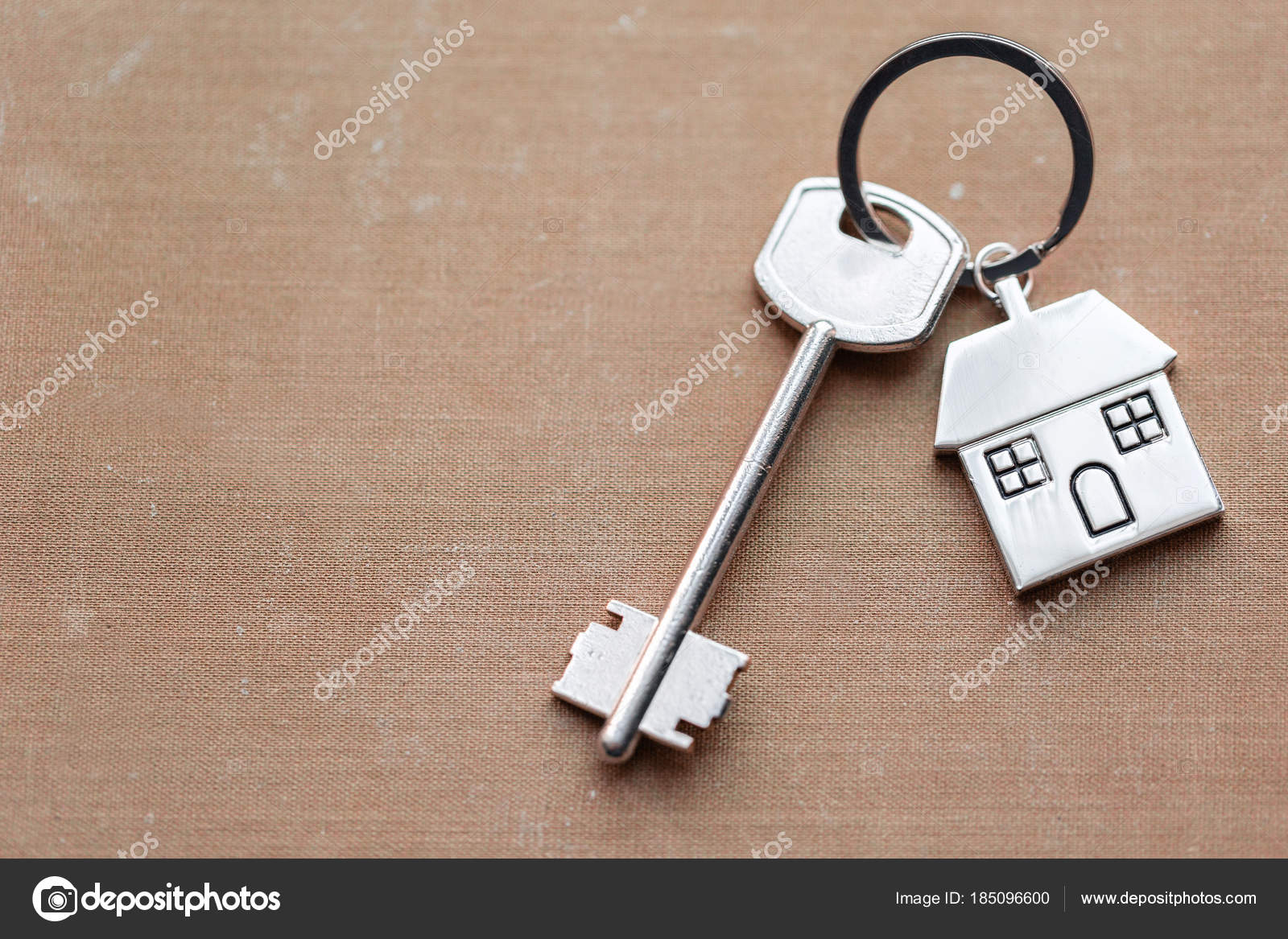 House key and keychain in the form of homes lies on fabric. Concept for
