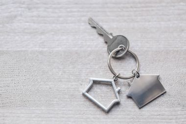 Ev anahtarı ve anahtarlık ahşap tahtaların üzerinde. Gayrimenkul, ipotek, taşınma ya da ev kiralama kavramı.