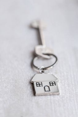 Ev anahtarı ve anahtarlık ahşap tahtaların üzerinde. Gayrimenkul, ipotek, taşınma ya da ev kiralama kavramı.