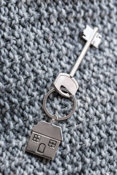 房子钥匙和钥匙串以房子的形式在针织羊毛织品。不动产、抵押、搬家或租赁财产的概念. — 图库照片