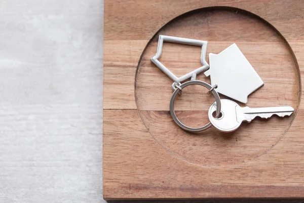 La llave de la casa y el llavero en forma de casas se encuentra en tablas de madera. Concepto de bienes raíces, hipoteca, mudanza o alquiler de propiedades . — Foto de Stock