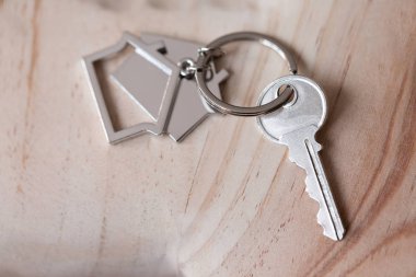 Ev anahtarı ve anahtarlık ahşap tahtaların üzerinde. Gayrimenkul, ipotek, taşınma ya da ev kiralama kavramı.