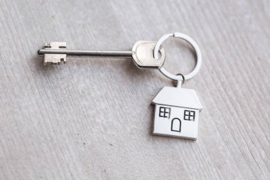 Ev anahtarı ve anahtarlık ahşap tahtaların üzerinde. Gayrimenkul, ipotek, taşınma ya da ev kiralama kavramı.