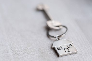 Ev anahtarı ve anahtarlık ahşap tahtaların üzerinde. Gayrimenkul, ipotek, taşınma ya da ev kiralama kavramı.