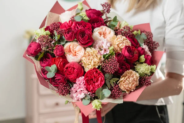 Bouquet of highly red coloured . beautiful luxury bunch of mixed flowers in womans hand. the work of the florist at a flower shop. — Stock Photo, Image