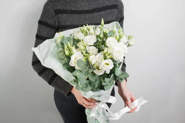 rich bouquet with eustoma lisianthus in woman hand . flowers and eucalyptus mint packaging