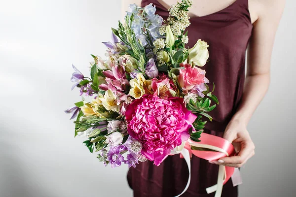 flower composition with peonies. Color pink, green, lavander, blue. beautiful luxury bouquet of mixed flowers in woman hand. the work of the florist at a flower shop