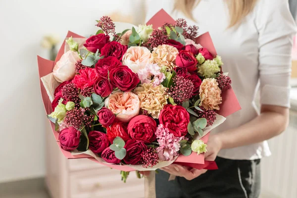 Bouquet of highly red coloured . beautiful luxury bunch of mixed flowers in womans hand. the work of the florist at a flower shop. — Stock Photo, Image