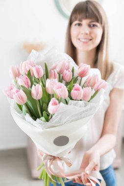 Güneşli bahar sabahı. Pembe Lale güzel bir grup ellerinde tutan genç mutlu kadın. Gülümsüyor kız için hediye. Çiçek buketi.