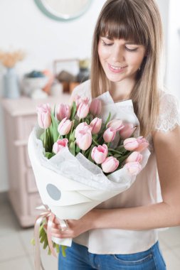 Güneşli bahar sabahı. Pembe Lale güzel bir grup ellerinde tutan genç mutlu kadın. Gülümsüyor kız için hediye. Çiçek buketi.