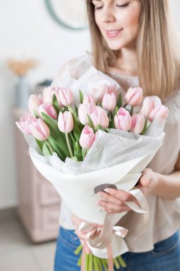 Güneşli bahar sabahı. Pembe Lale güzel bir grup ellerinde tutan genç mutlu kadın. Gülümsüyor kız için hediye. Çiçek buketi.