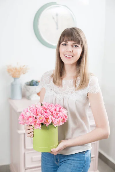 Manhã de primavera ensolarada. Jovem mulher feliz segurando um belo bando de tulipas rosa em suas mãos. Um presente para uma rapariga sorridente. Buquê de flores na caixa de cabeça — Fotografia de Stock