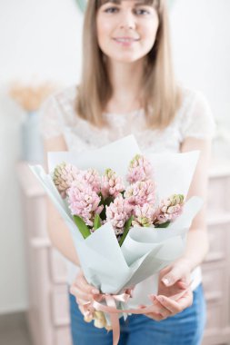 Güneşli bahar sabahı. Pembe sümbül güzel bir grup ellerinde tutan genç mutlu kadın. Gülümsüyor kız için hediye. Çiçek buketi.