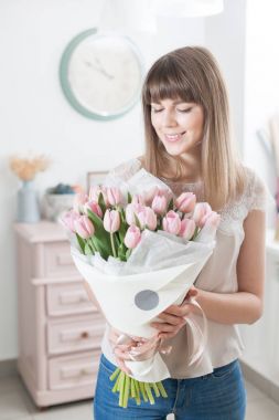 Güneşli bahar sabahı. Pembe Lale güzel bir grup ellerinde tutan genç mutlu kadın. Gülümsüyor kız için hediye. Çiçek buketi.